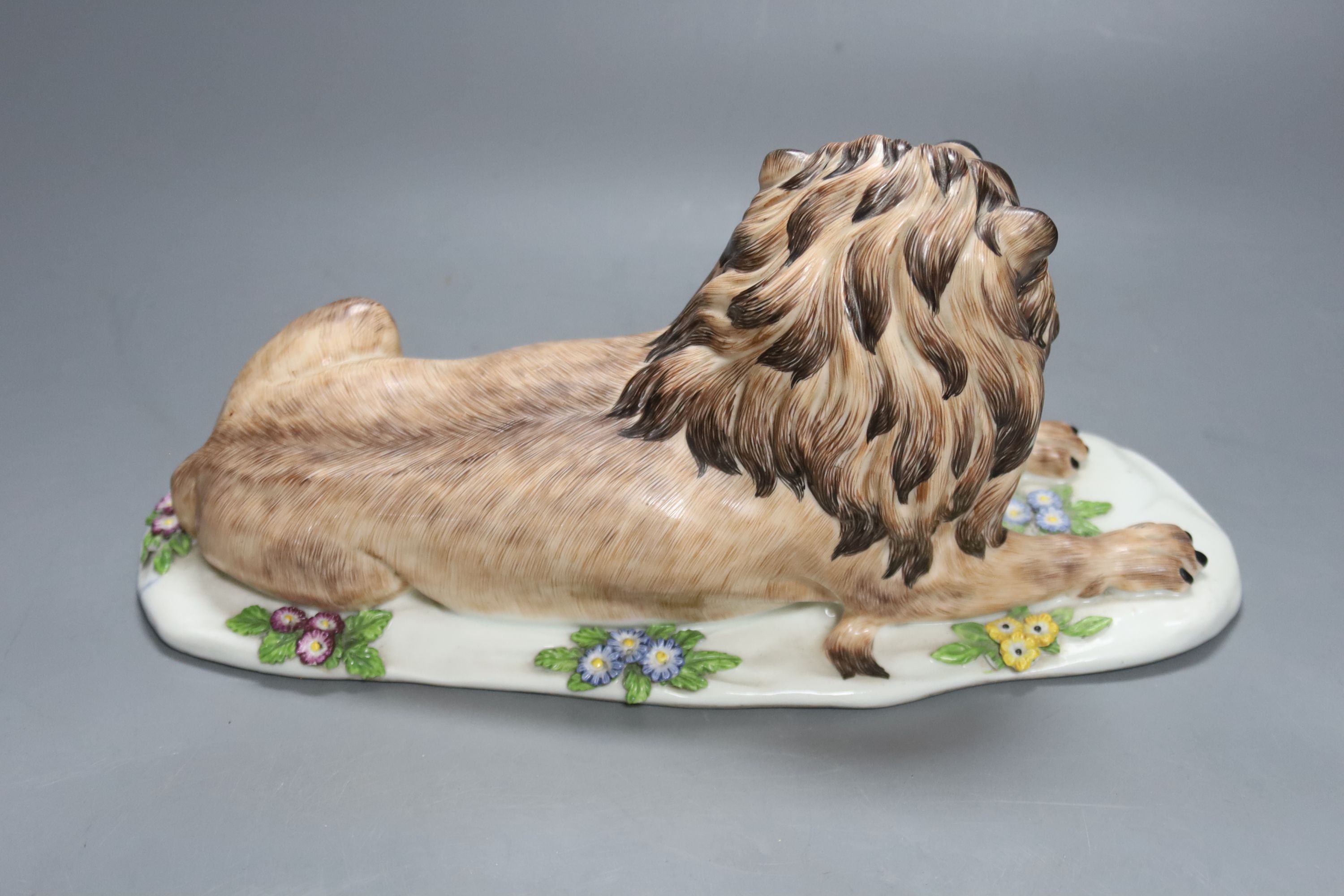 A Meissen style porcelain recumbent lion, 30 cms wide.